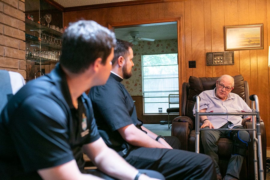seminarians speaking with a retired priest in his home